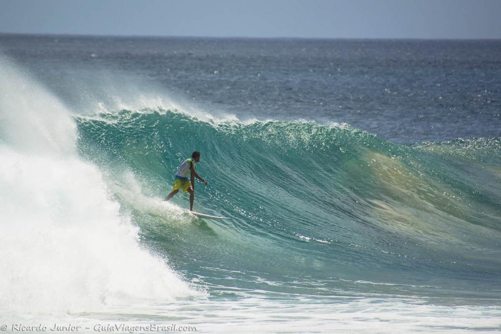 Imagem de uma surfista e o vento batendo no topo das ondas.